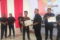 Ketua panitia, Deni Hendra Sitepu (kanan) menyerahkan piagam penghargaan kepada salah seorang peserta kejuaraan menembak, Kamis (26/6/2025).