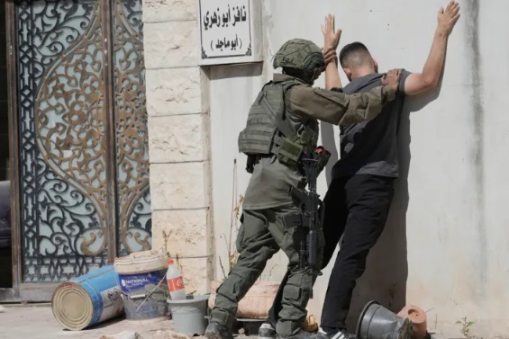 Seorang tentara Israel menggeledah seorang pria Palestina di kamp pengungsi Tulkarem, Tepi Barat yang diduduki, pada 6 Juli. (Sumber foto: Majdi Mohammad/AP Photo)