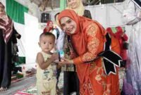 Ny. Lismawani Al-Farlaky, S.Pd., M.Ag., saat menyapa salah seorang anak di kegiatan Sosialisasi Wajib Belajar 13 Tahun di Kecamatan Peureulak, Aceh Timur, Kamis (4/9/2025).