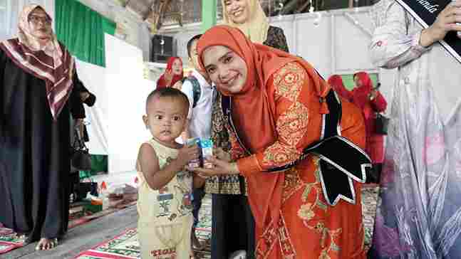 Ny. Lismawani Al-Farlaky, S.Pd., M.Ag., saat menyapa salah seorang anak di kegiatan Sosialisasi Wajib Belajar 13 Tahun di Kecamatan Peureulak, Aceh Timur, Kamis (4/9/2025).