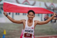 Pelari Indonesia Yad Hafizudin berlari mengibarkan bendera Merah Putih usai memenangkan lomba lari kategori pria 1.500 meter U 20 pada event kejuaraan Atletik Asia Tenggara U-18 & U-20 di Stadion Madya Atletik Kawasan Sport Centre Sumut, Kabupaten Deliserdang, Provinsi Sumatera Utara, Sabtu (15/11/2025). 