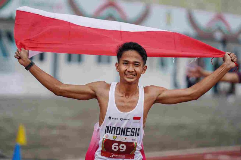 Pelari Indonesia Yad Hafizudin berlari mengibarkan bendera Merah Putih usai memenangkan lomba lari kategori pria 1.500 meter U 20 pada event kejuaraan Atletik Asia Tenggara U-18 & U-20 di Stadion Madya Atletik Kawasan Sport Centre Sumut, Kabupaten Deliserdang, Provinsi Sumatera Utara, Sabtu (15/11/2025). 
