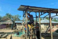 Personel Batalyon C Satuan Brimob Polda Sumatera Utara saat bantu warga memasang atap seng.