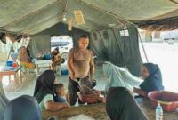 Seorang personi brimob sedang melayani warga di tenda lapangan di Desa Aek Ngadol, Kecamatan Batang Toru, Kabupaten Tapanuli Selatan. Pada Rabu, 28 Januari 2026