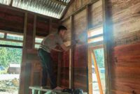 Salah seorang personel sedang mengerjakan rehab dinding rumah hunian sementara.