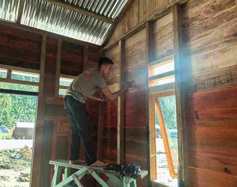 Salah seorang personel sedang mengerjakan rehab dinding rumah hunian sementara.