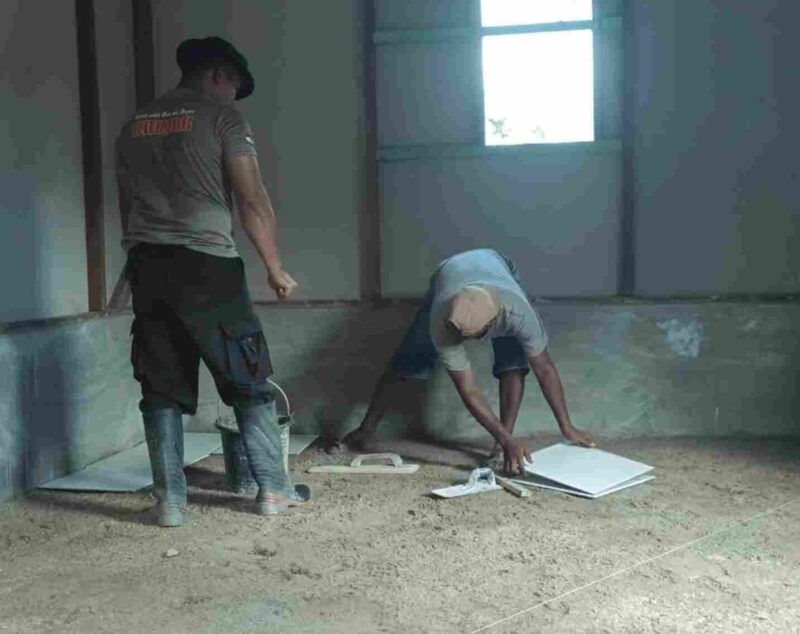 Personil brimob bantu warga merehab lantai rumah. 