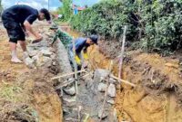 Personel Satgas TMMD dan masyarakat setempat bergotong royong melakukan penggalian dan pembentukan saluran.