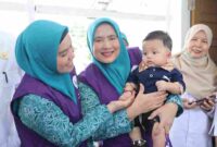 Ketua Tim Posyandu Kabupaten Asahan saat tinjau dan gendong salah seorang anak balita.