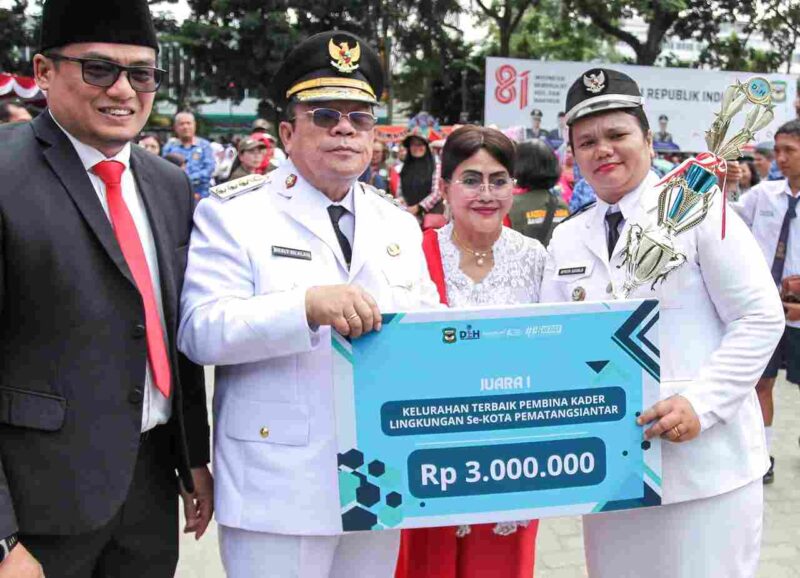 Wali kota Pematangsiantar, wesly Silalahi, SH.,M.Kn, didampingi Istri dan kadis LH Kota pematangsiantar Arri Sembiring, S.STP.,M.Si saat menyerahkan Piala dan hadiah kepada Lurah Kahean, Aprita pronika Sagala, S.Si., M.Si. pada Hut RI ke 81 Tahun di lapangan Adam Malik Pematangsiantar.