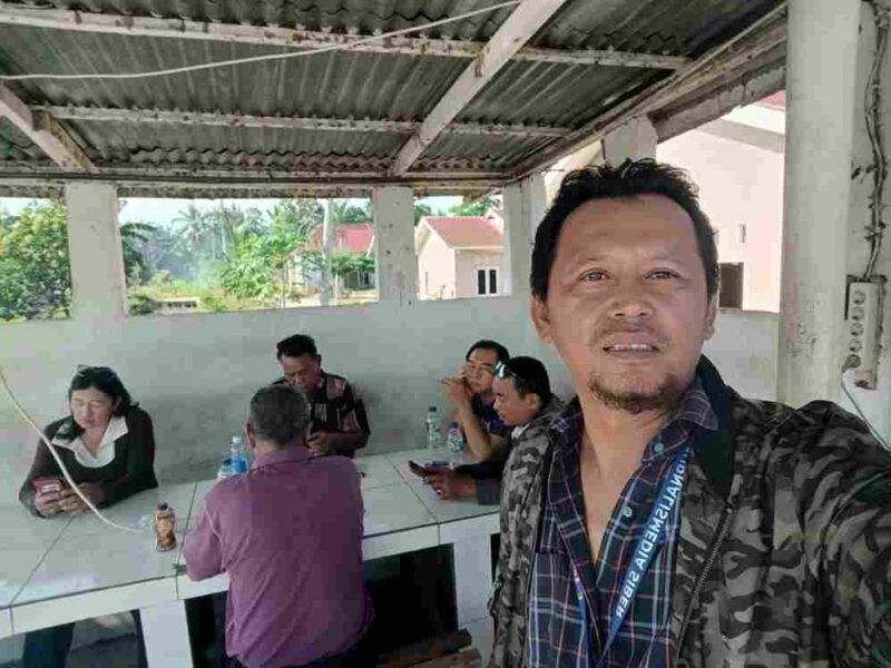 Sosok Akiang saat duduk dan diapit wartawan. 